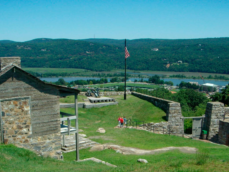 An outdoor view of the scenery outside of the West Point Museum with a US flag and a river in the background.